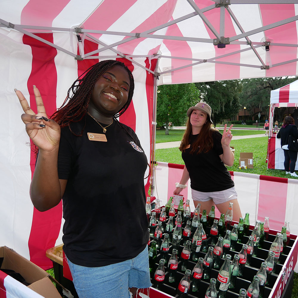  Two students running a game at an outdoor carnival event